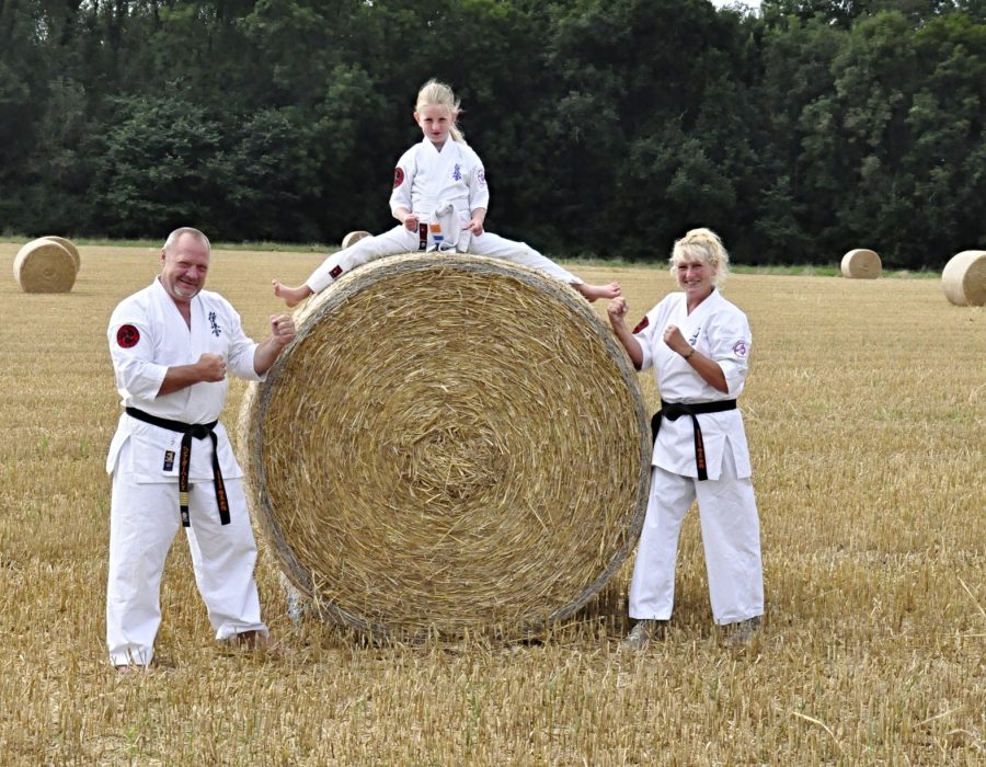 Henk, Conny en een jonge karateka bij een strobaal